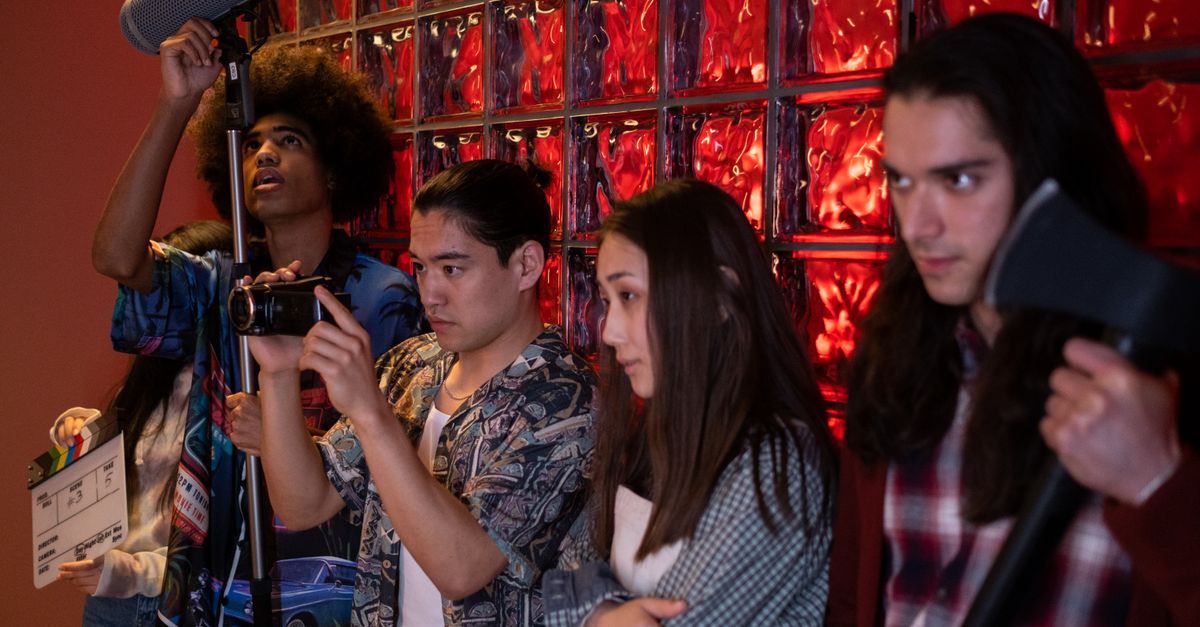 Group of teens pretending a movie scene in an indoor setting, showcasing diversity and creative teamwork.